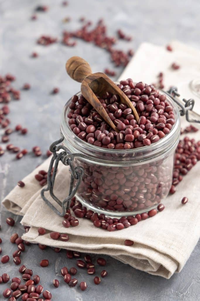 Adzuki beans in a jar with a wooden scoop