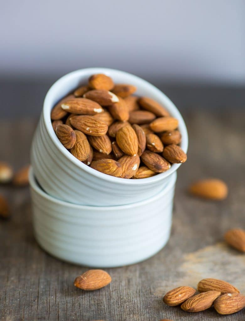 A bowl of almonds sitting on a wooden countertop