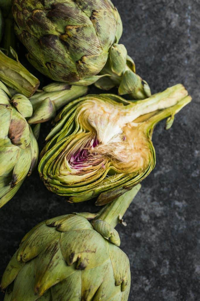 Halved artichoke surrounded by whole artichokes