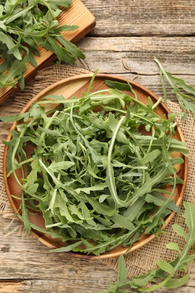 Fresh arugula leaves scattered on a wooden table