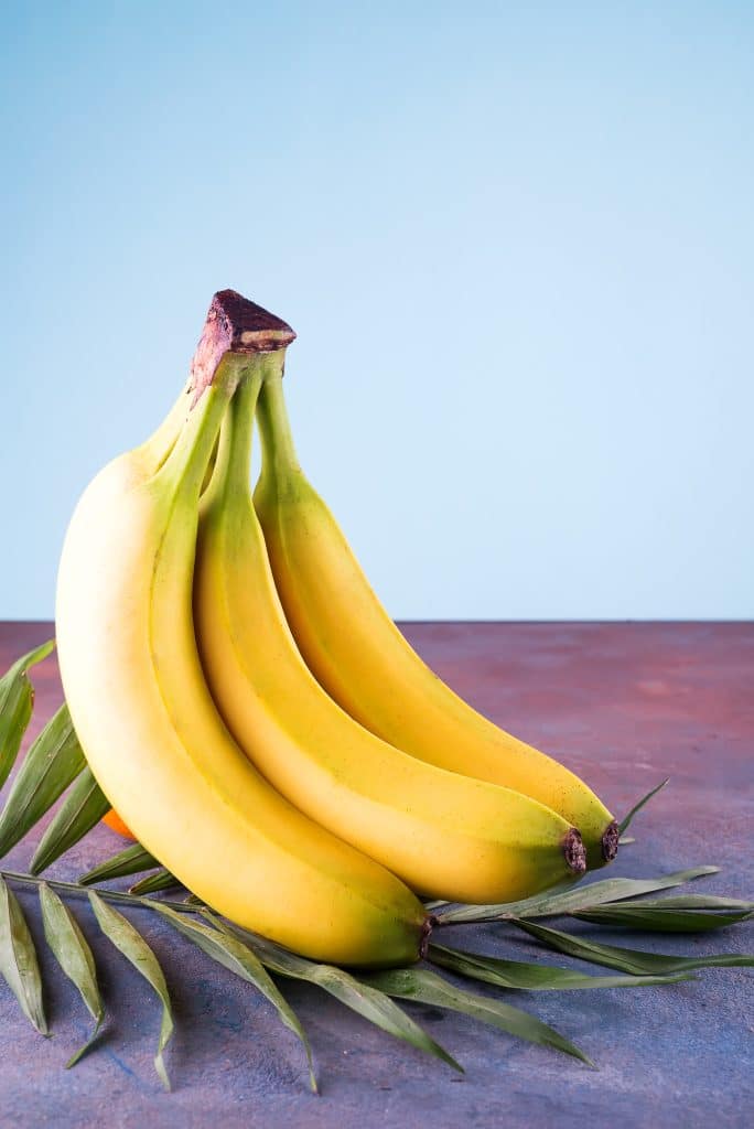 A bunch of fresh bananas against green palm leaves