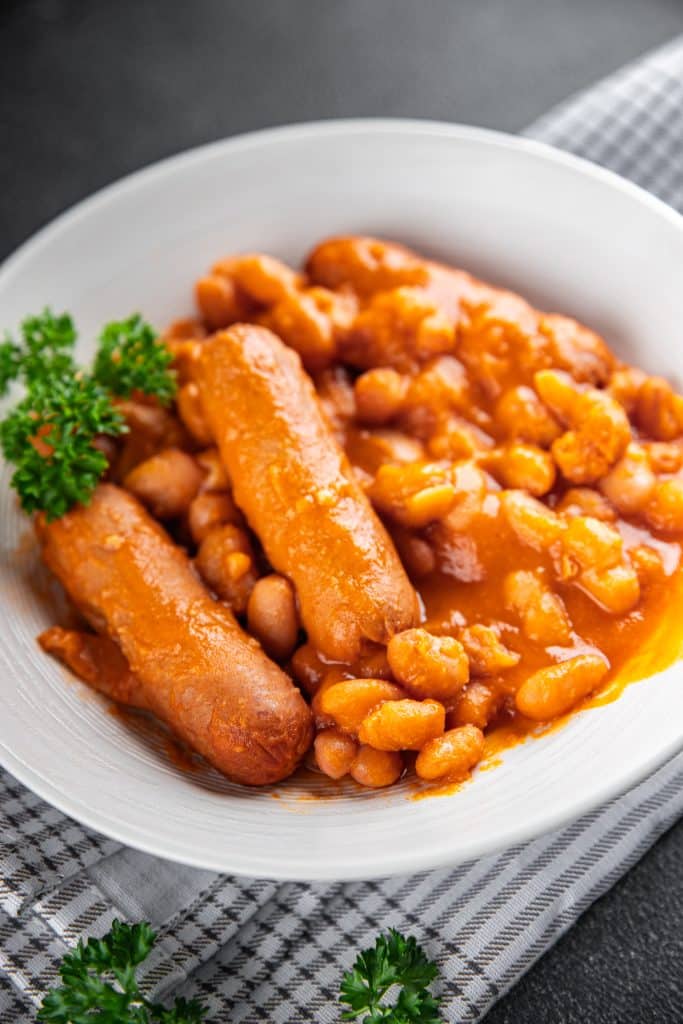 A skillet of baked beans with sliced hot dogs