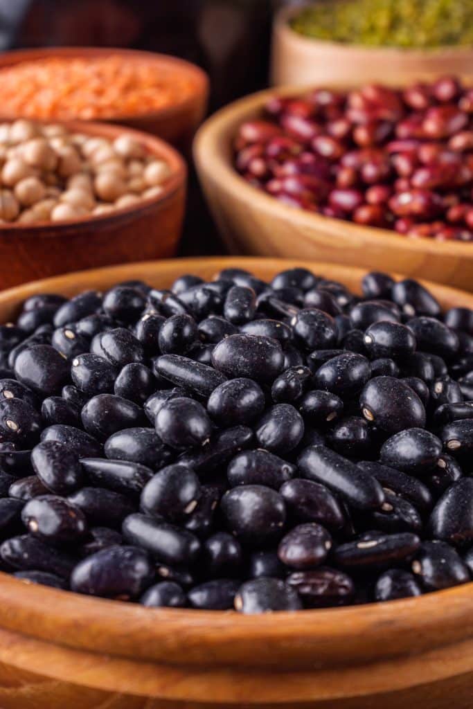 Wooden bowl of black beans among other legumes