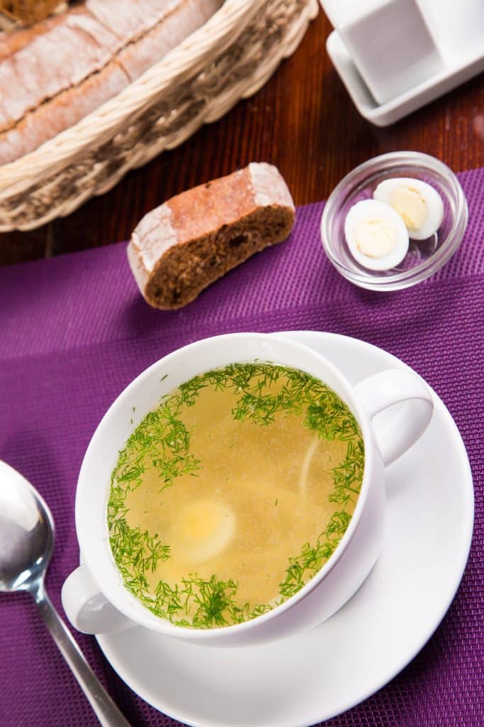 Bowl of chicken soup with bread and a soft egg