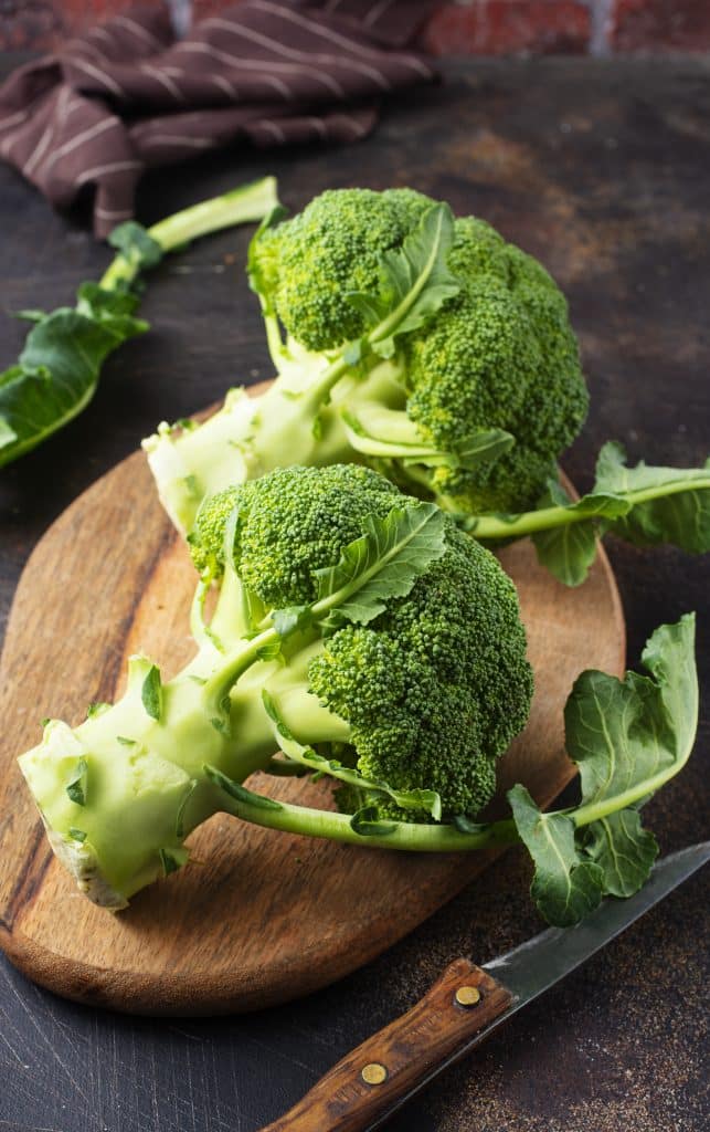 Broccoli crowns on a wooden cutting board