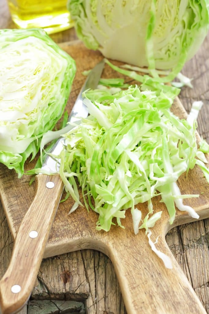 A head of cabbage with a slightly flattened side and loose outer leaves