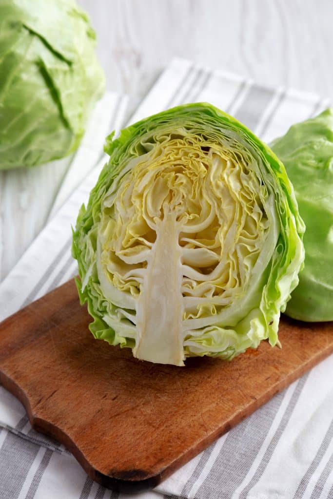 A whole head of raw cabbage on a wooden board