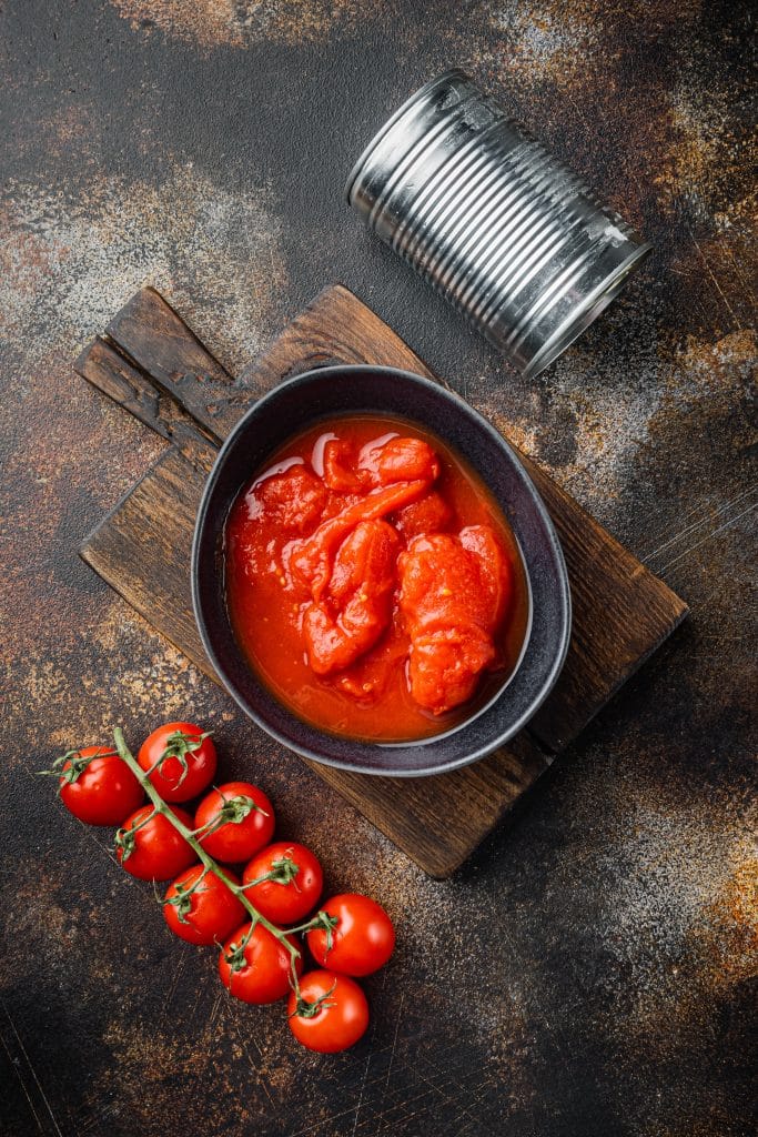 Whole canned tomatoes on a rustic dark background