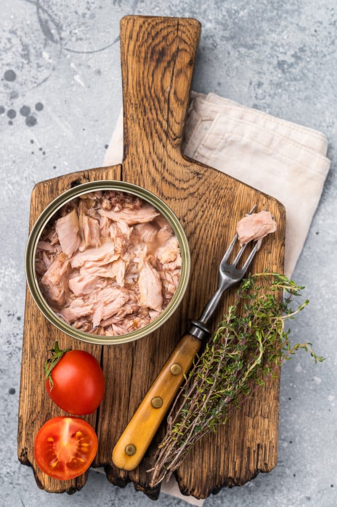 Canned tuna with tomatoes and thyme on a cutting board