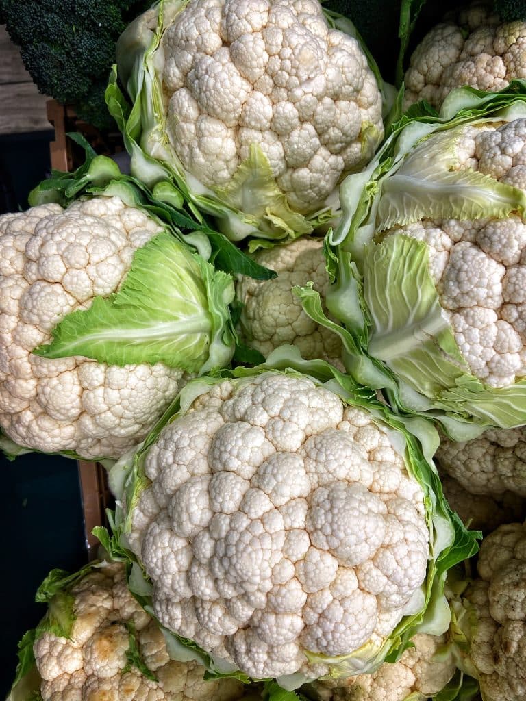 Cauliflower heads with green leaves at a market