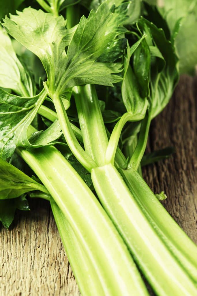 Fresh celery stalks on a rustic wooden surface
