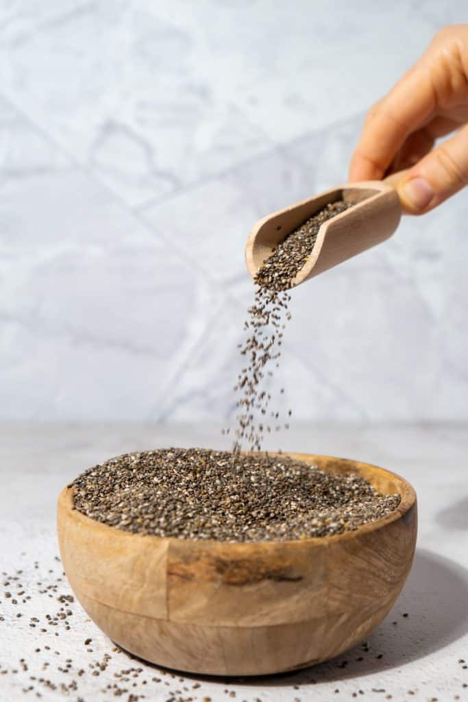 Chia seeds being poured into a bowl from a scoop