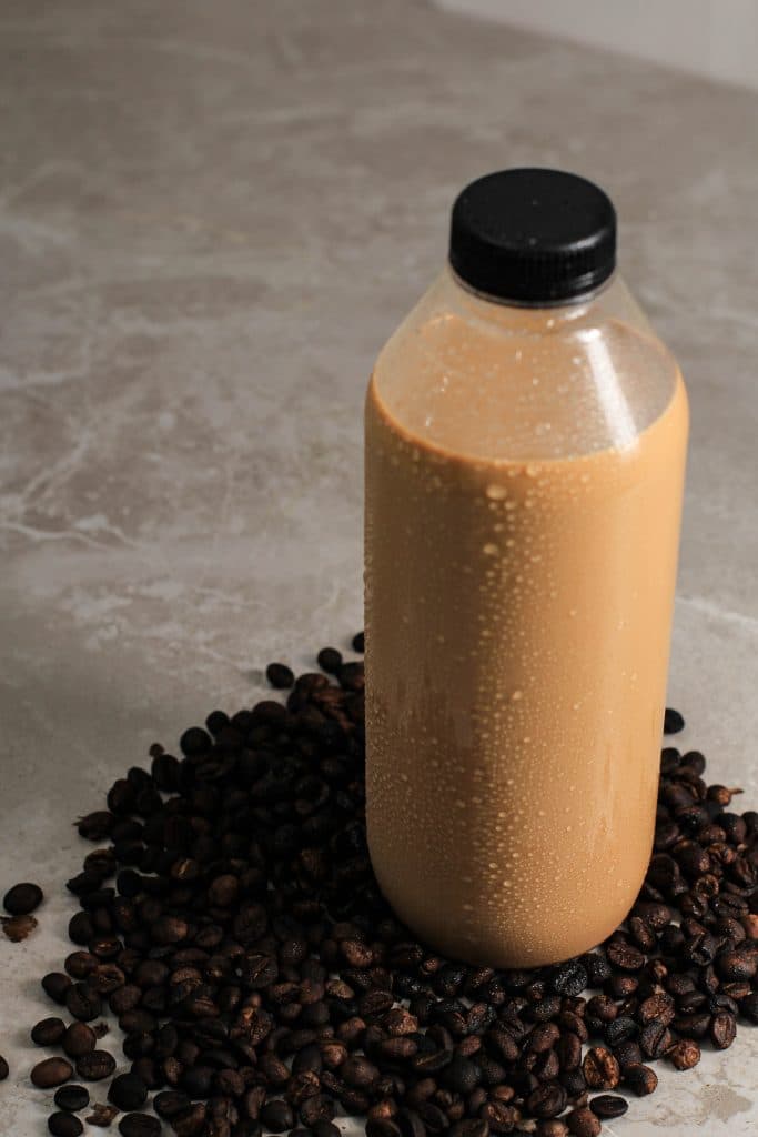 bottle of coffee creamer next to loose coffee beans