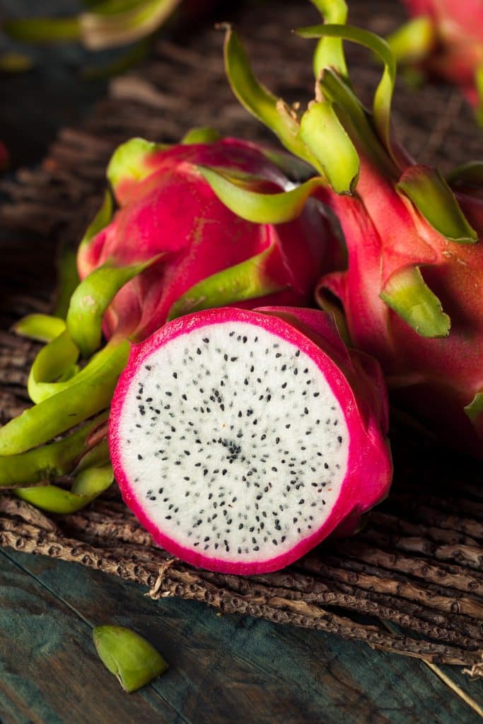 Fresh dragon fruit sliced open on a wooden surface