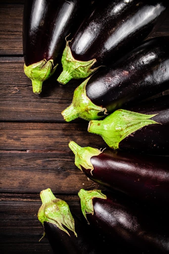 Fresh whole eggplants lined up on a table