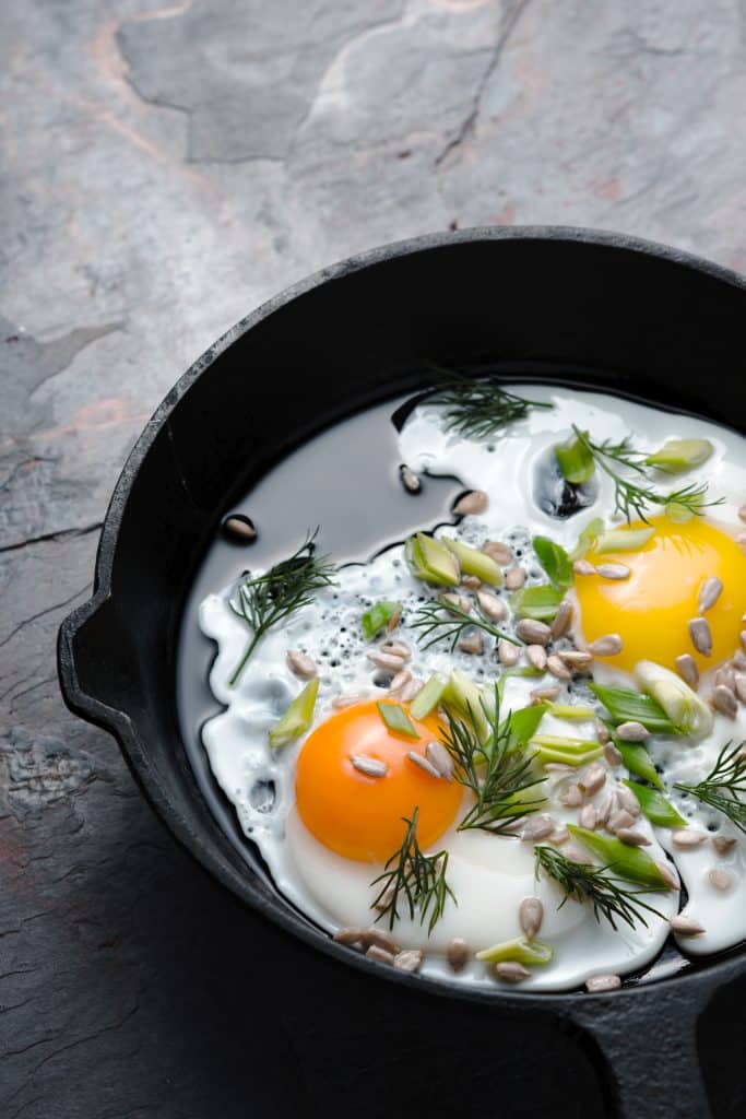 Fried eggs topped with fresh herbs and seeds