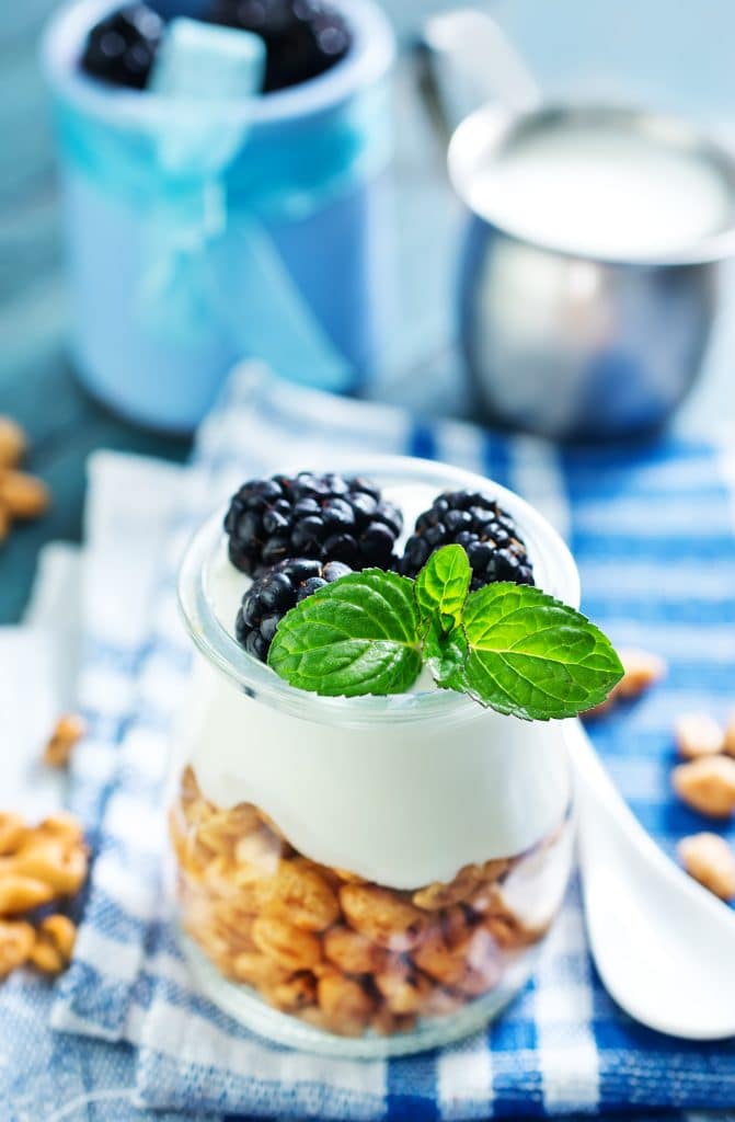 A yogurt parfait layered with berries, granola, and mint