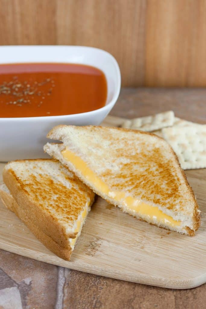 Grilled cheese sandwich beside a bowl of tomato soup