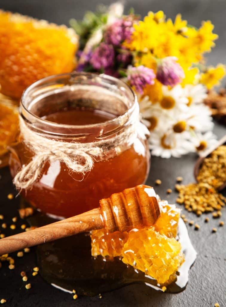 Golden honey in a glass jar with a wooden dipper
