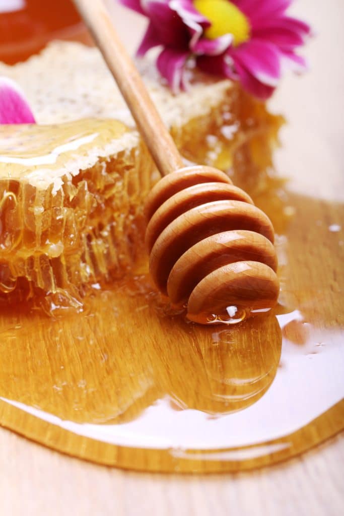 Honeycomb with honey and a wooden dipper