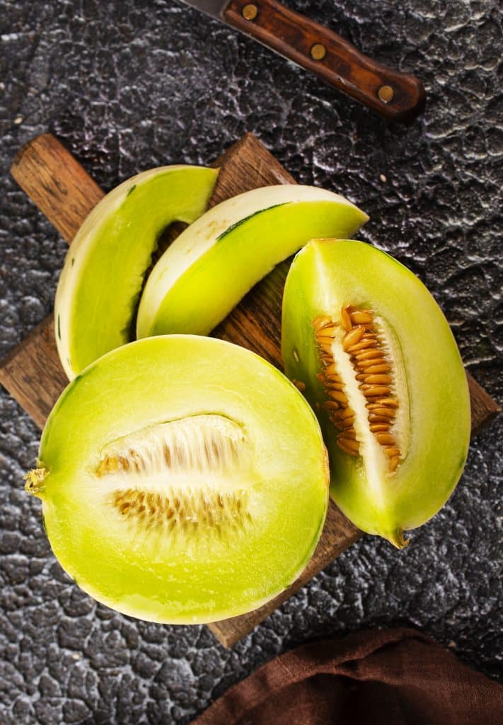 Sliced honeydew melon on a wooden cutting board