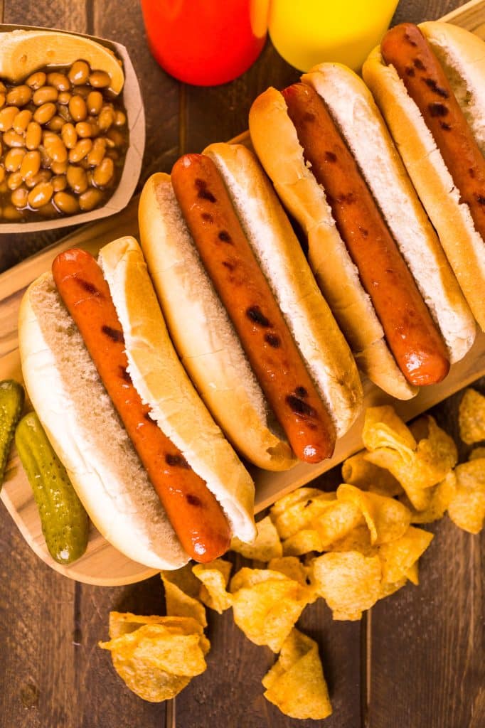 Grilled hot dogs in buns lined up on a board