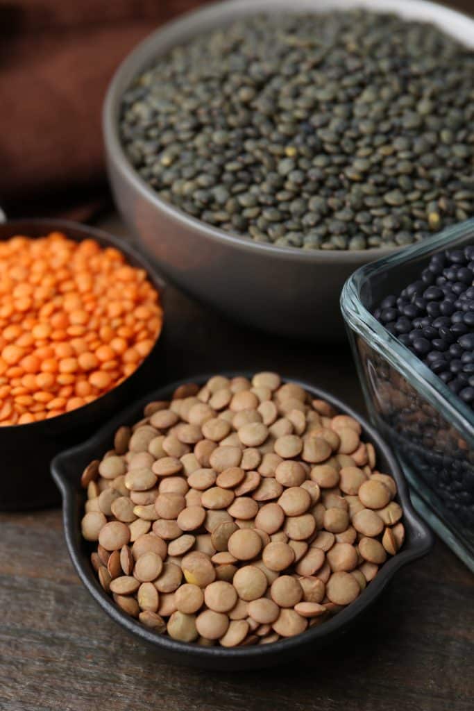 Bowls of assorted dried lentils on a wooden table