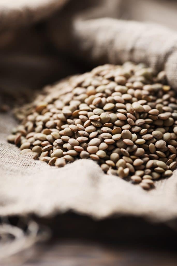 A pile of dry lentils on a burlap cloth