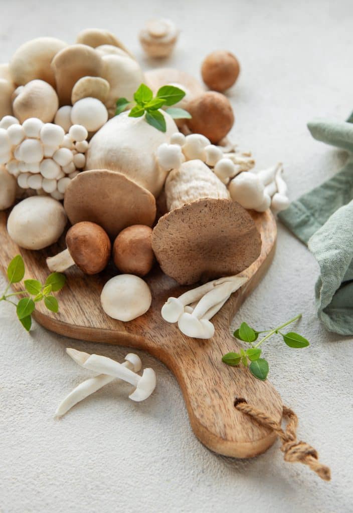An assortment of mushrooms laid out on a wooden cutting board