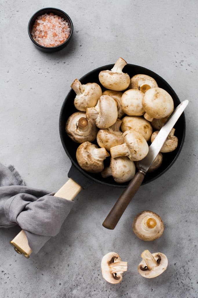 Mushrooms next to a frying pan and salt
