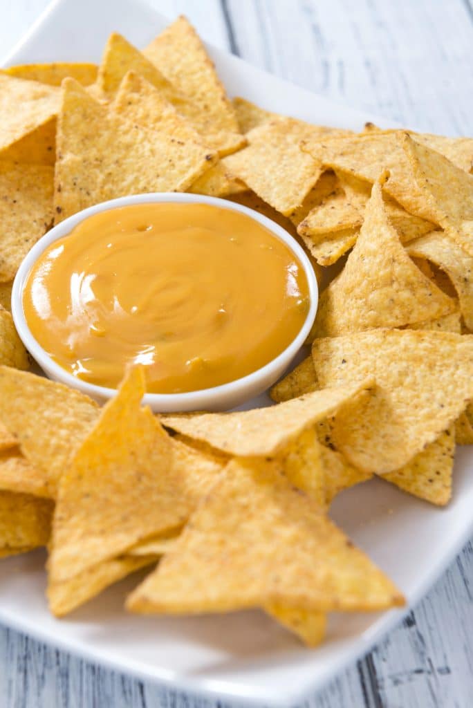A tray of nachos covered in cheese sauce