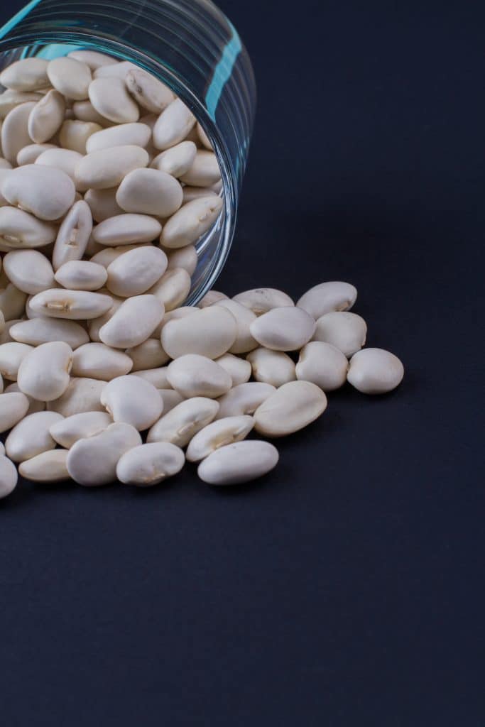 White navy beans spilling from a glass jar