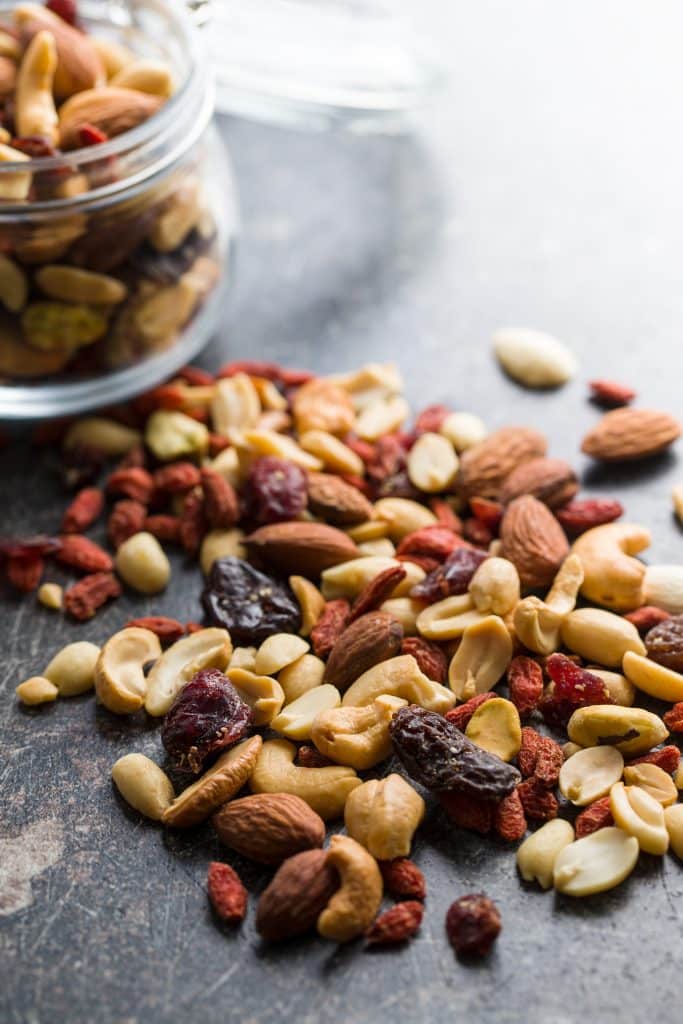 Assorted nuts and dried berries spilling from a glass jar