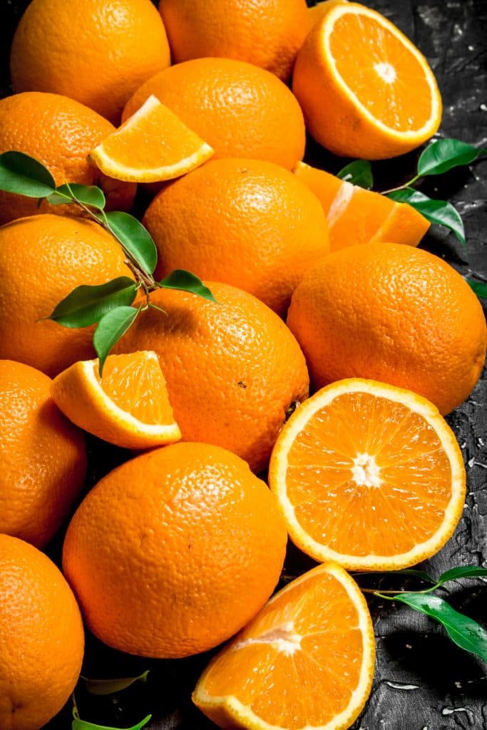 Pile of fresh oranges with leaves attached