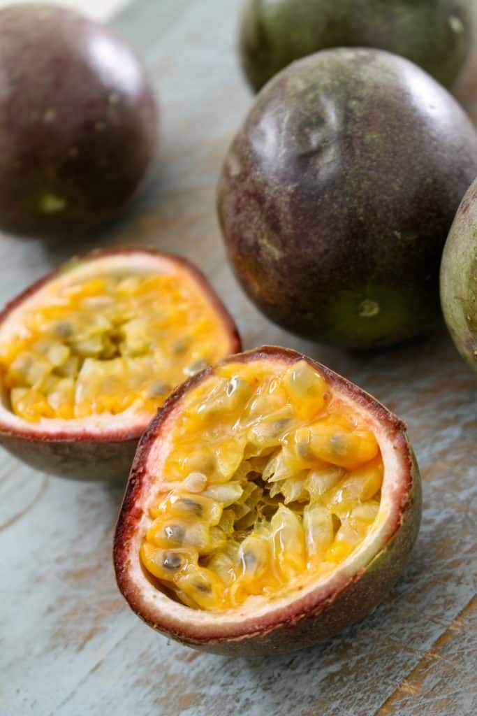 A ripe passion fruit cut open on a wooden table