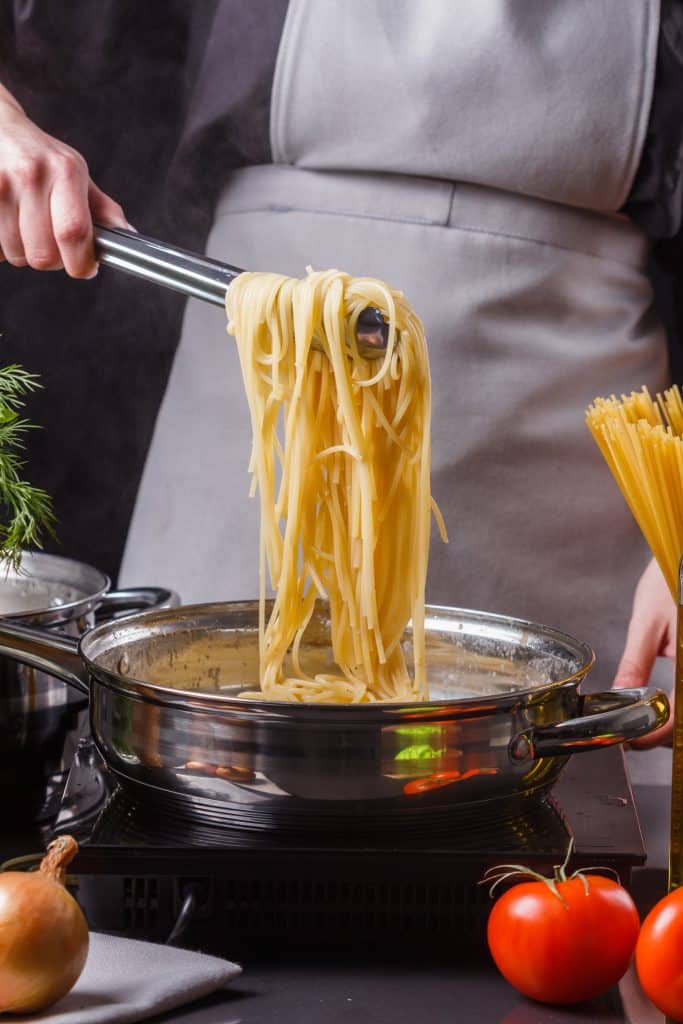Chef cooking pasta in a busy kitchen
