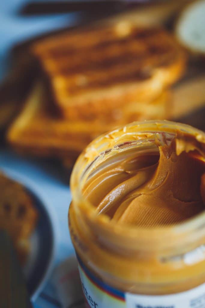 A jar of peanut butter beside slices of toast