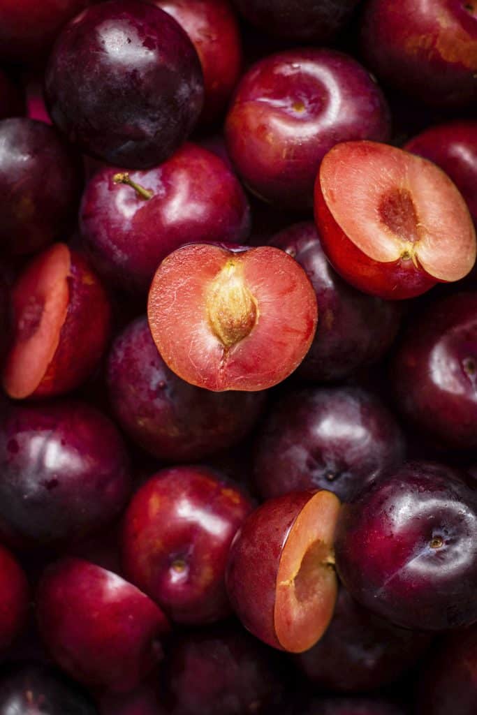 Whole and halved plums showing their flesh