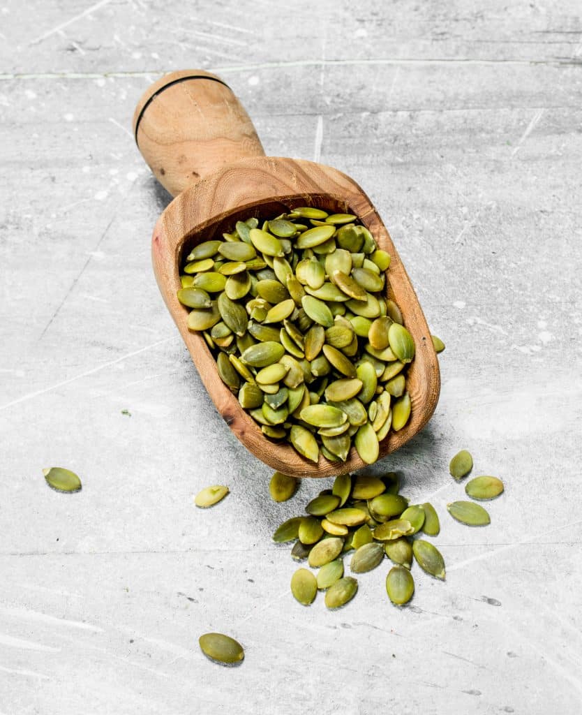 A wooden scoop full of pumpkin seeds