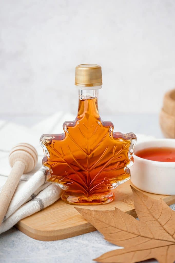 Bottle of pure maple syrup poured into a dish
