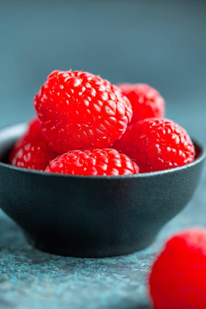 Raspberries in a black ceramic bowl