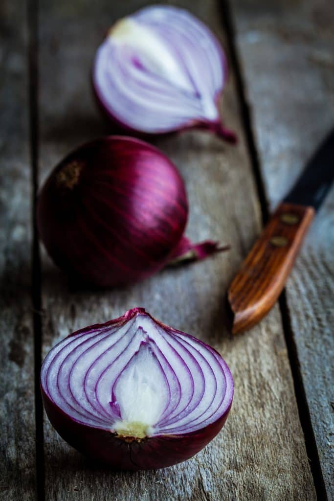 Whole red onions on a rustic wood table