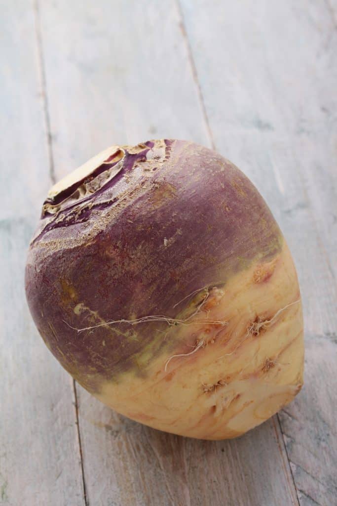 A whole rutabaga on a light wooden surface