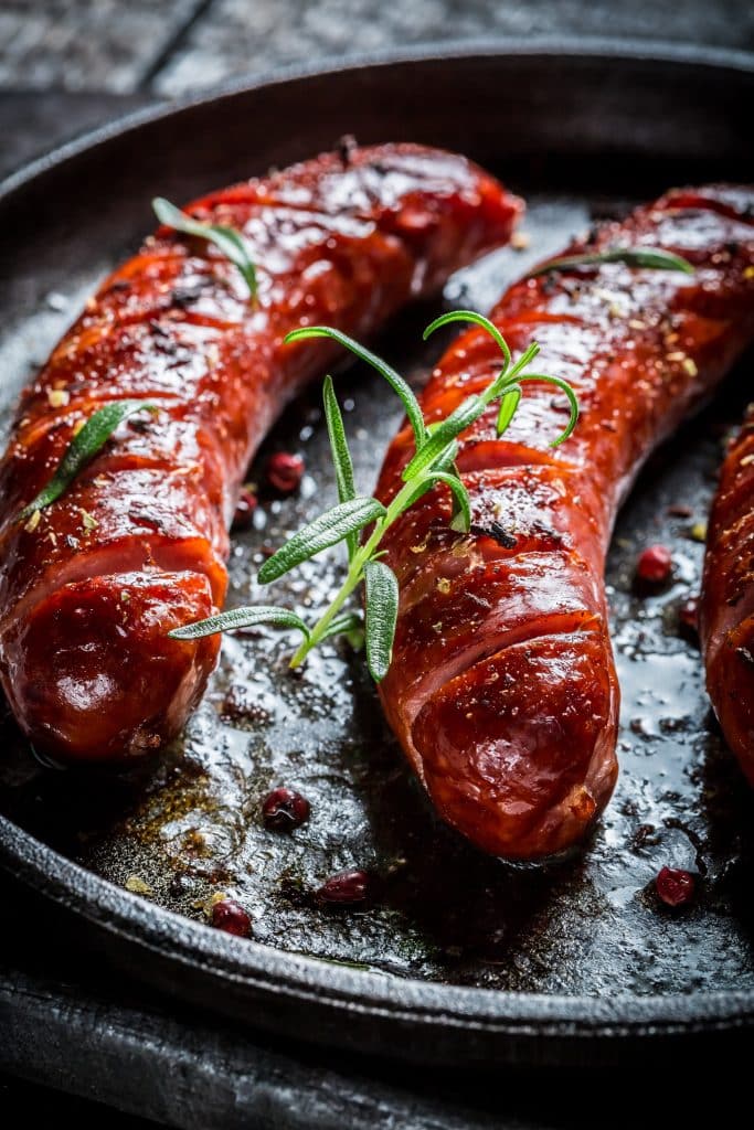 Browned sausages with herbs in a cast iron pan