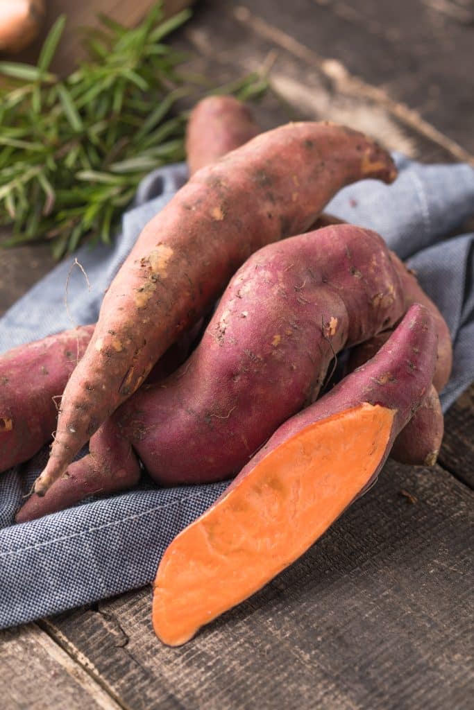 Raw sweet potato on a wooden chopping board