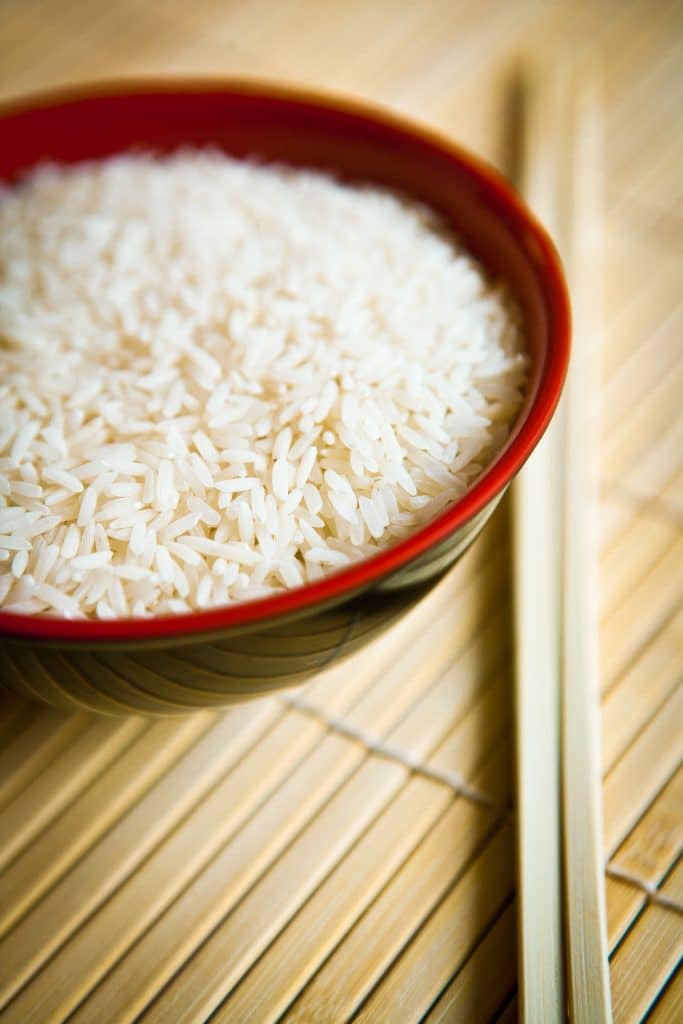 A bowl of cooked white rice with chopsticks