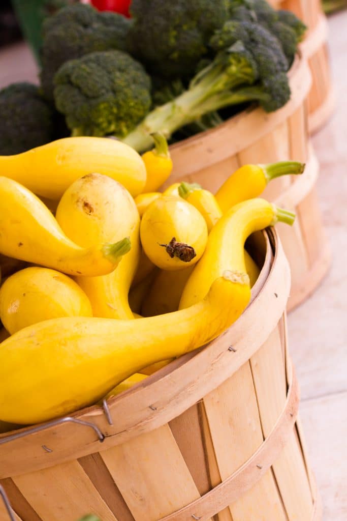 Bright yellow squash next to fresh broccoli